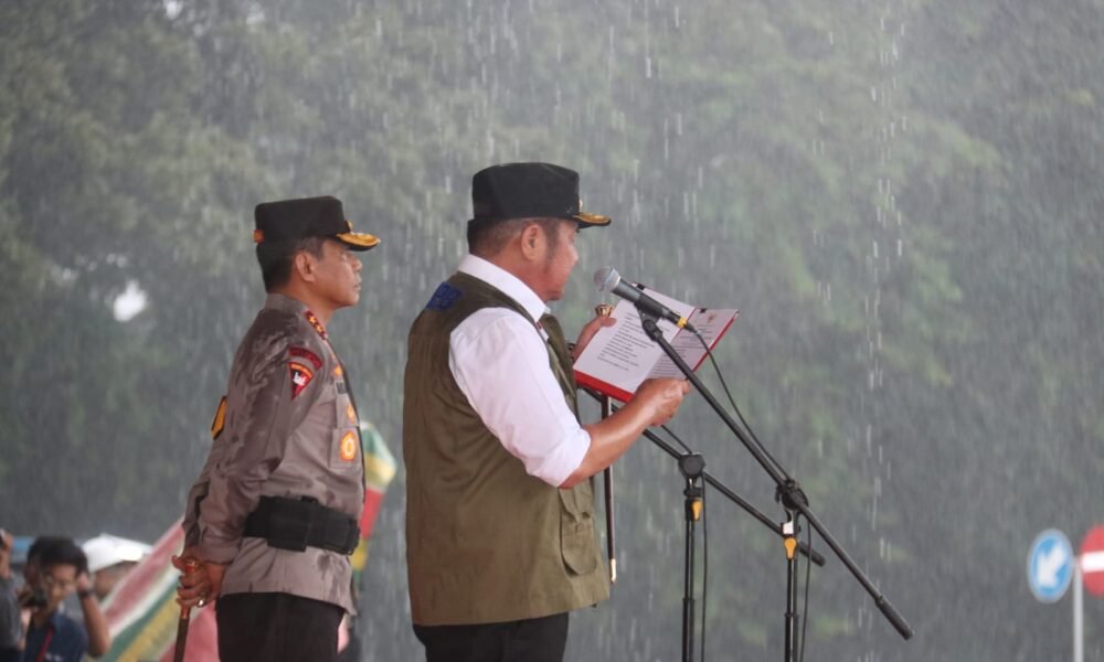 Meski diguyur hujan deras, Kapolda Sumsel Irjen Pol Andi Rian R Djajadi bersama Gubernur Sumatera Selatan H Herman Deru memimpin Apel Gelar Pasukan Operasi Lilin Musi 2025 di halaman Griya Agung Palembang, Jumat (19/12/2025).