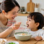 Lansia Wajib Tahu! 5 Manfaat Berjemur di Pagi Hari agar Tetap Sehat dan Bugar Seorang ibu memberikan semangkuk bubur hangat kepada anak saat sarapan pagi dengan suasana dapur yang cerah. (Foto: dok/nara.sriwijayaterkini.id)